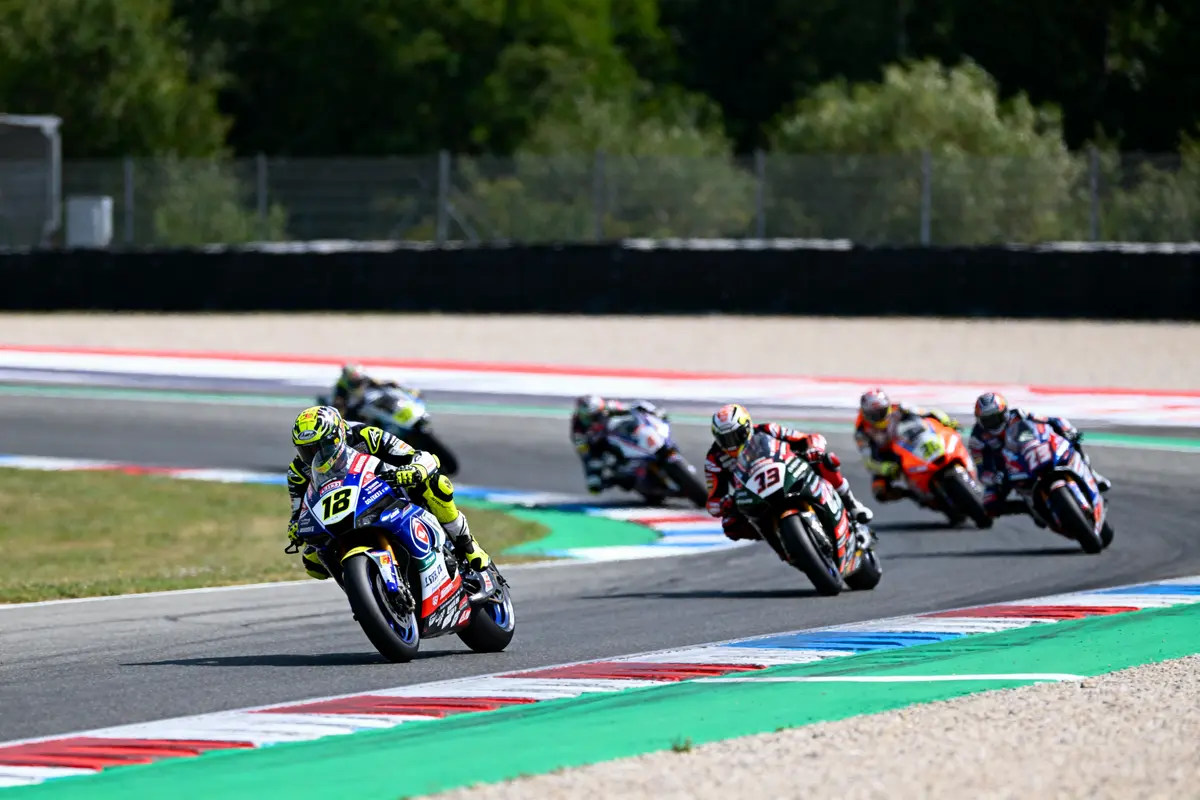 Course de motos sur circuit, six pilotes inclinent dans un virage serré au milieu d'une course dynamique.