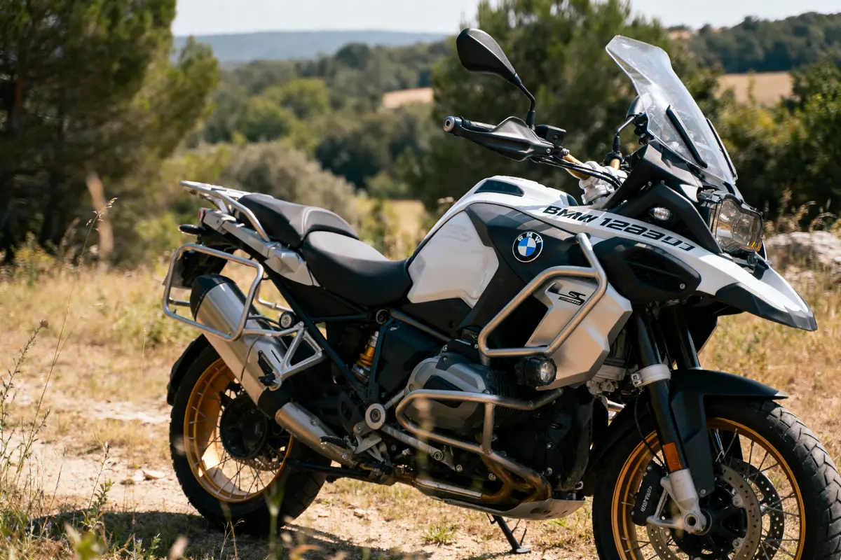 Moto BMW blanche stationnée sur un chemin de campagne, entourée de verdure et d'arbres.