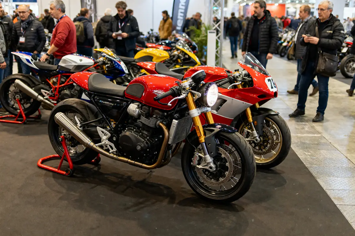 Salon de la moto, plusieurs motos rouges exposées, visiteurs observant, intérieur avec éclairage brillant et sol gris.