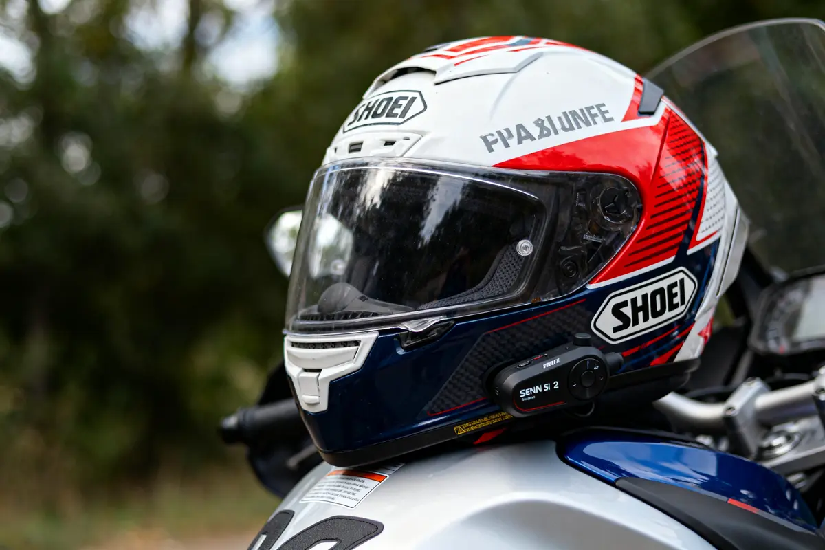 Casque de moto Shoei avec intercom Sena installé, posé sur une moto.