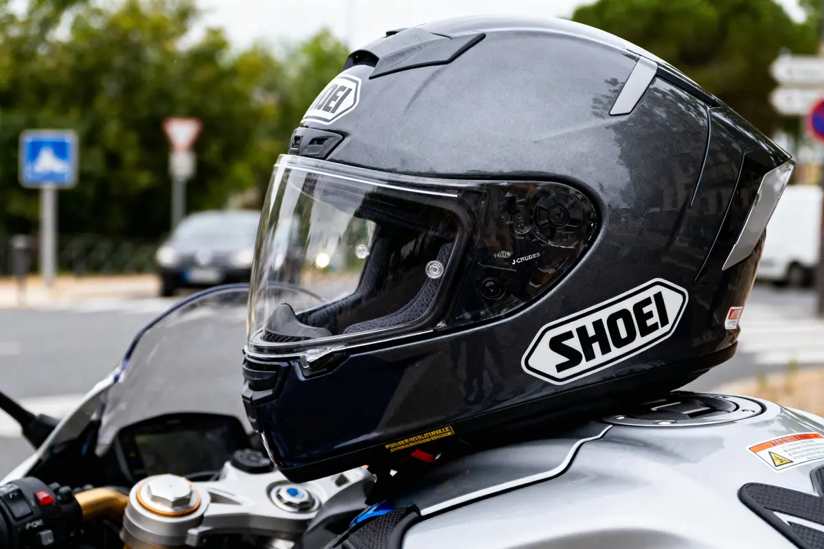 Casque de moto Shoei noir et gris sur une moto sur fond urbain flou.
