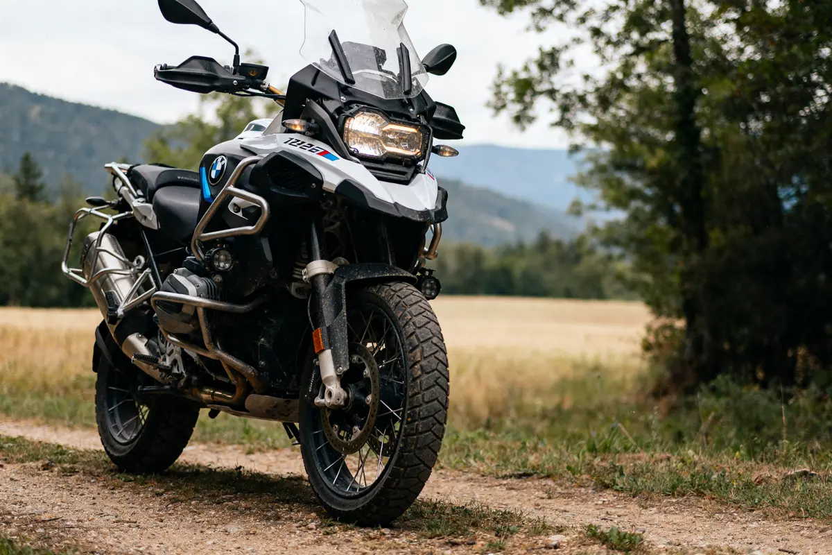 Moto BMW R 1200 GS Adventure sur chemin de terre en campagne verdoyante