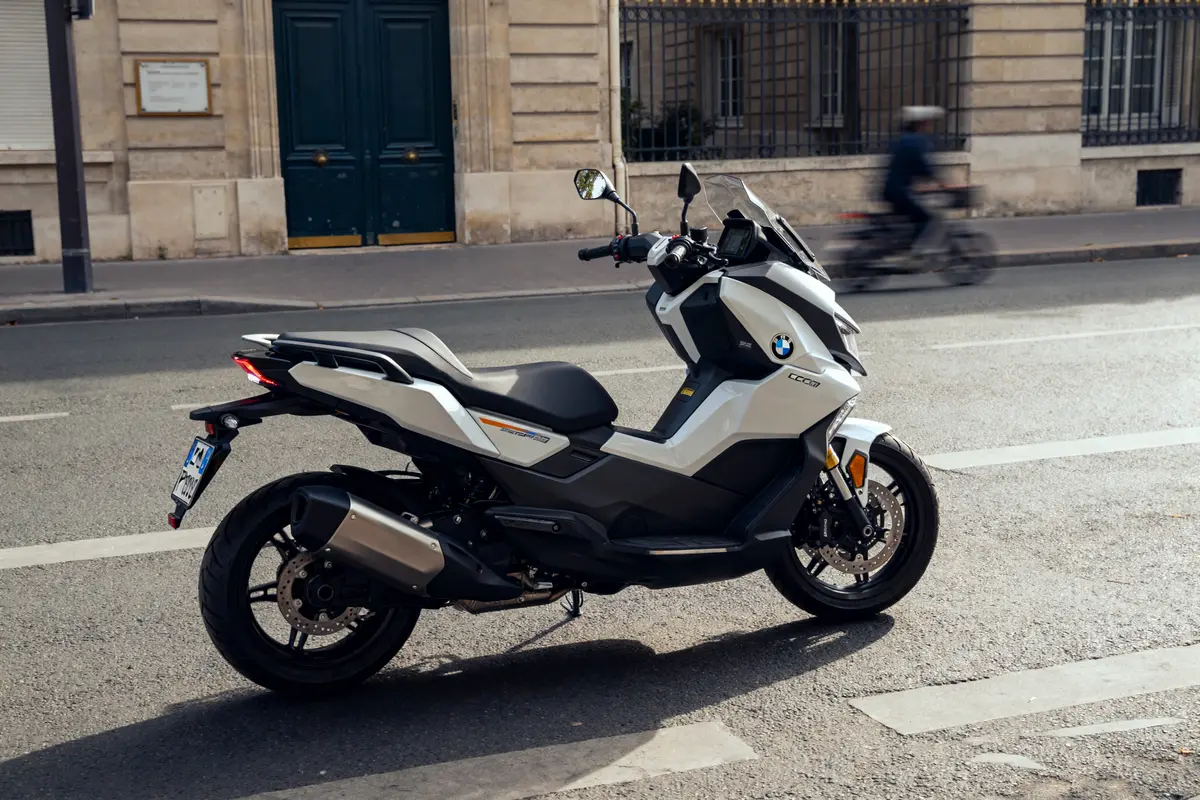 Scooter électrique urbain BMW ce04 stationné en ville sur une route pavée