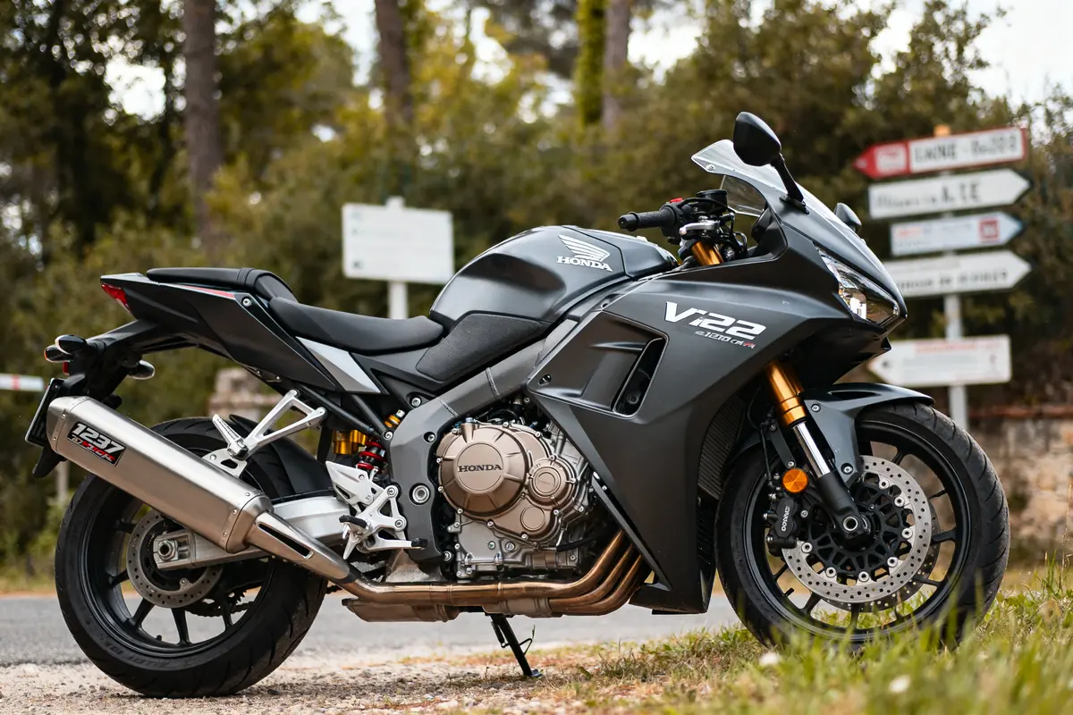 Moto Honda VFR 1200 noire stationnée sur une route avec des panneaux en arrière-plan