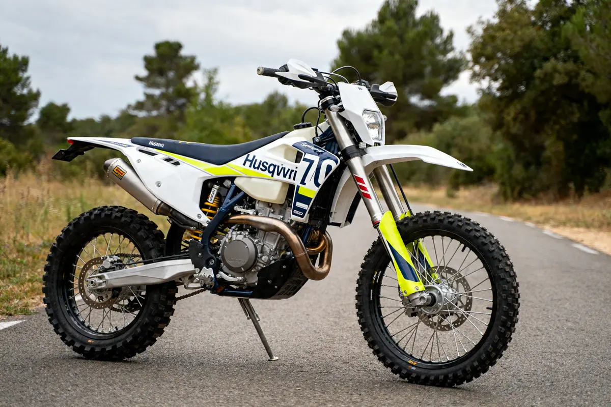 Moto Husqvarna 701 Supermoto sur une route, entourée de verdure et arbres