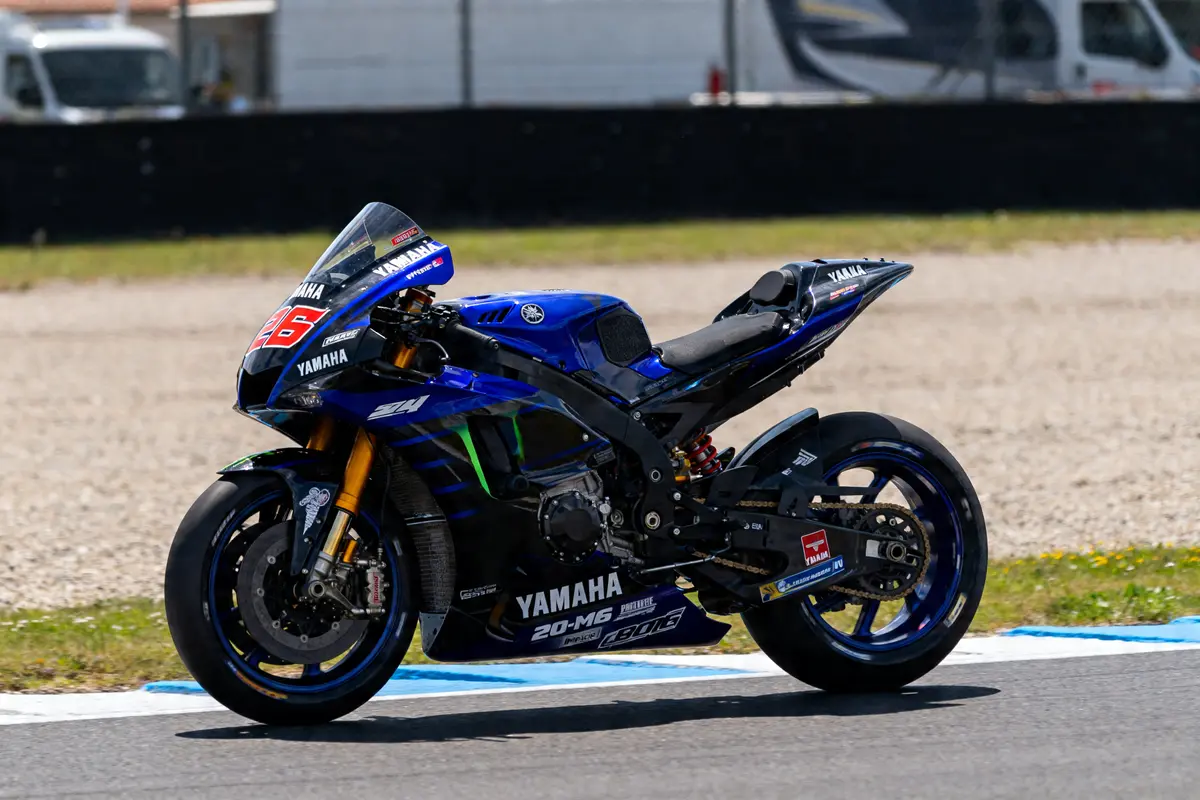 Moto sportive Yamaha YZR-M1 bleue sur circuit, vue de profil sur piste ensoleillée