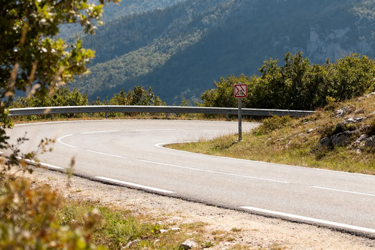 Route sinueuse au col de fontbruno bordée de montagnes et panneaux de signalisation