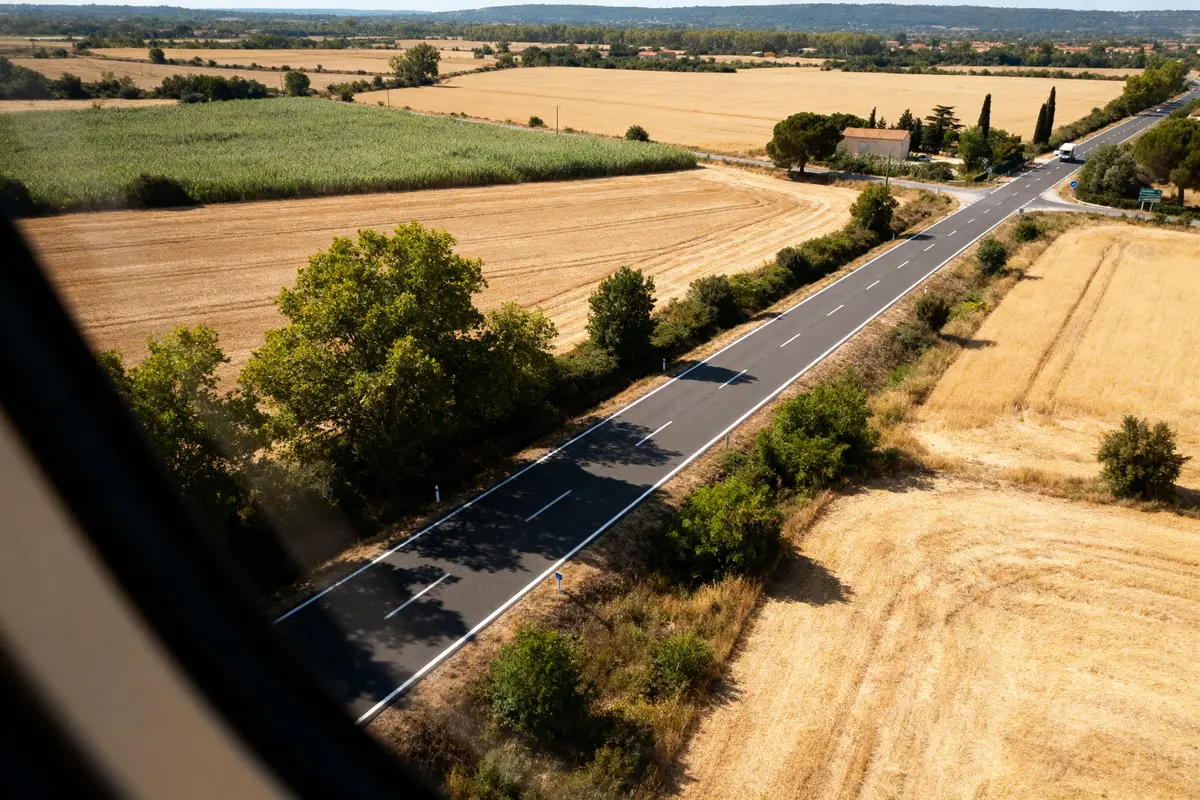 Route rurale entre champs, illustrant la distance Toulouse Montpellier en plein été lumineux