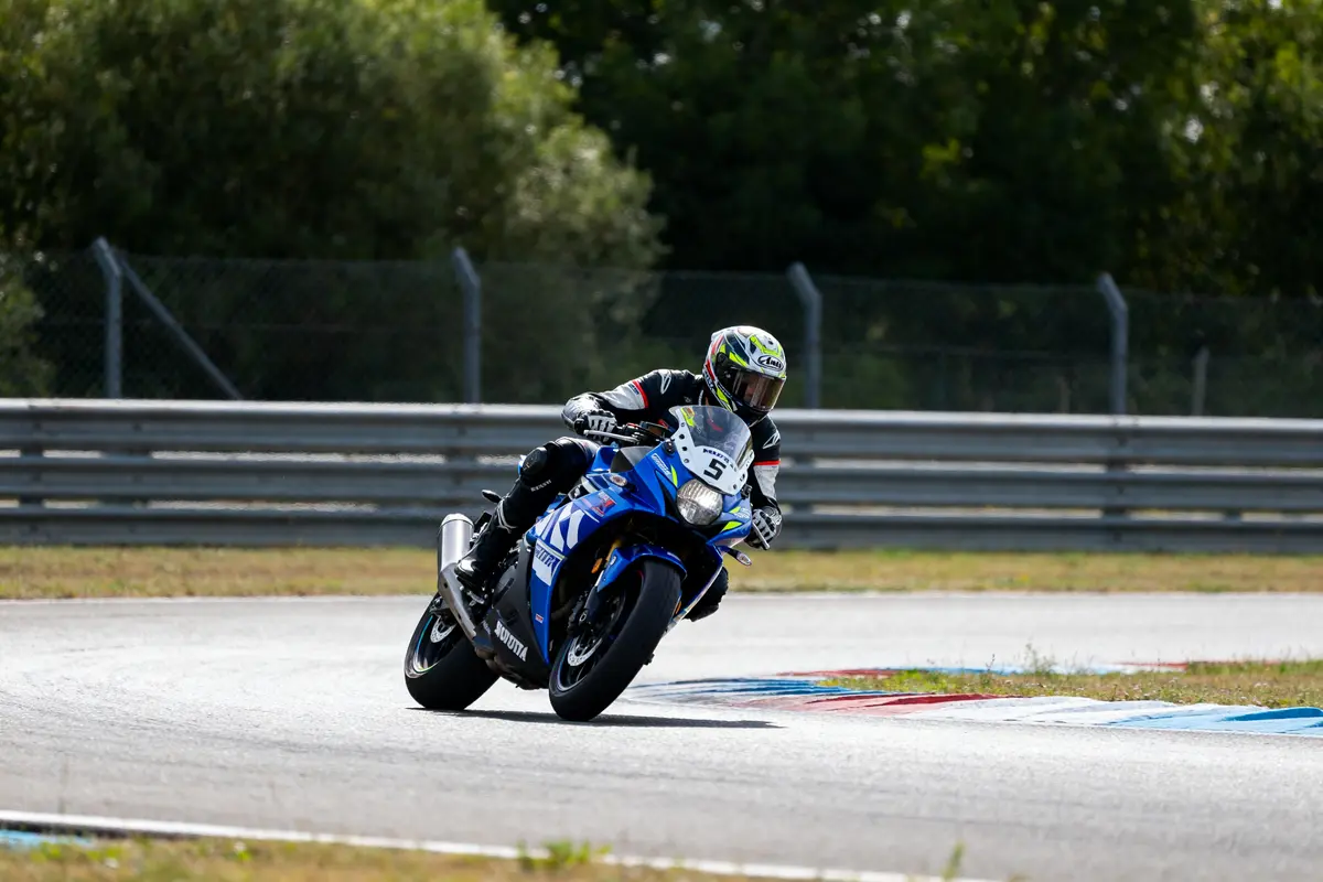 Pilote de mgb moto bleue en virage sur circuit avec protections et casque