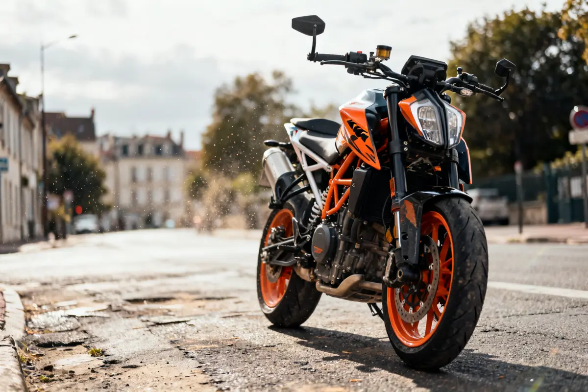 Moto duke690 garée sur une route, jantes orange vives en plein soleil urbain