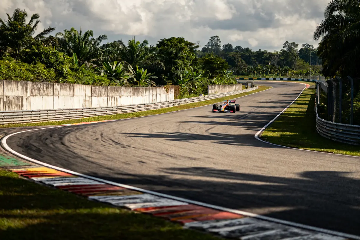 Voiture de course sur une courbe du Sepang Circuit Malaysia entourée de verdure tropicale