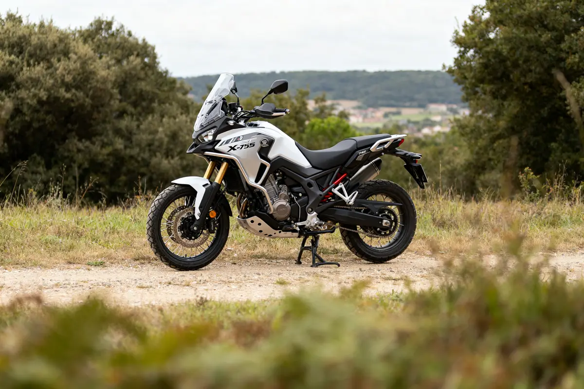 Moto Honda X-ADV 750 blanche garée sur chemin avec paysage naturel en arrière-plan