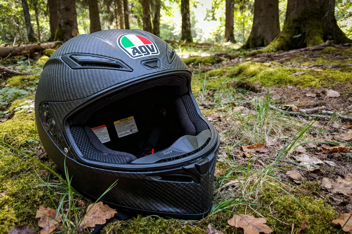 Casque moto AGV K6 en forêt sur sol mousseux et feuillu.