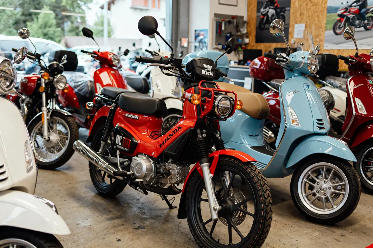 Motos et scooters alignés en showroom avec kick moto sur modèle rouge au premier plan
