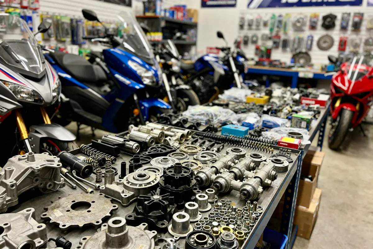 Pièces détachées moto sur table avec motos en arrière-plan dans magasin We Moto