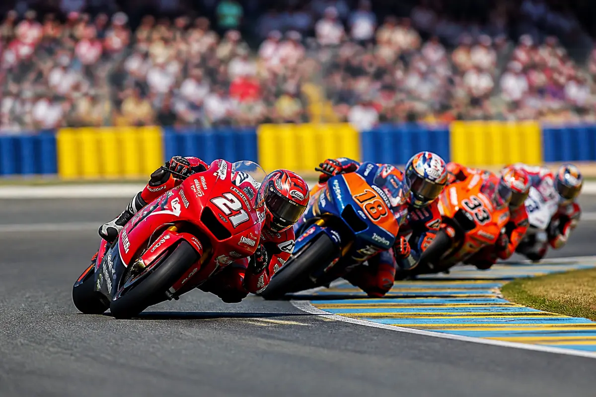 Des motos de course en virage lors d'une compétition avec spectateurs flous en arrière-plan.